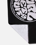 Esquina de la toalla Rip Curl Logos Towel negra mostrando reverso blanco y lazo para colgar