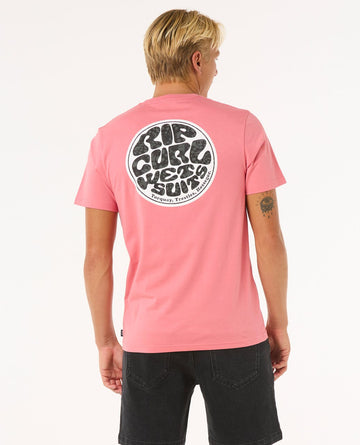 Modelo con camiseta Rip Curl Wettie Passage Icon Tee rosa, vista trasera, estampado grande en la espalda con logo Rip Curl.