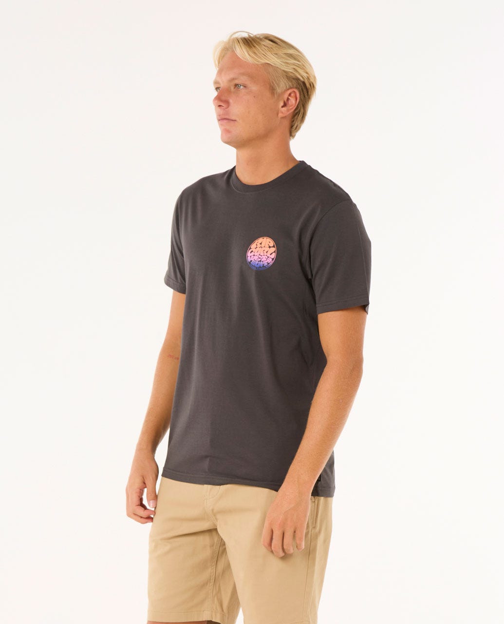 Modelo con camiseta Rip Curl Wettie Passage Icon Tee negra, vista lateral, ajuste estándar, algodón orgánico.