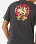 Camiseta Rip Curl Shaper Address Tee negra, look completo con pantalón corto negro y zapatillas.