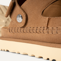 Detalle del empeine de ante marrón claro y costura artesanal de las sandalias UGG Goldenstar Glide para mujer