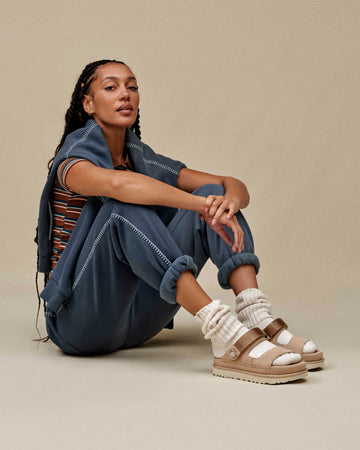 Mujer con look urbano y sandalias UGG Goldenstar Glide marrón claro, combinación con chándal azul