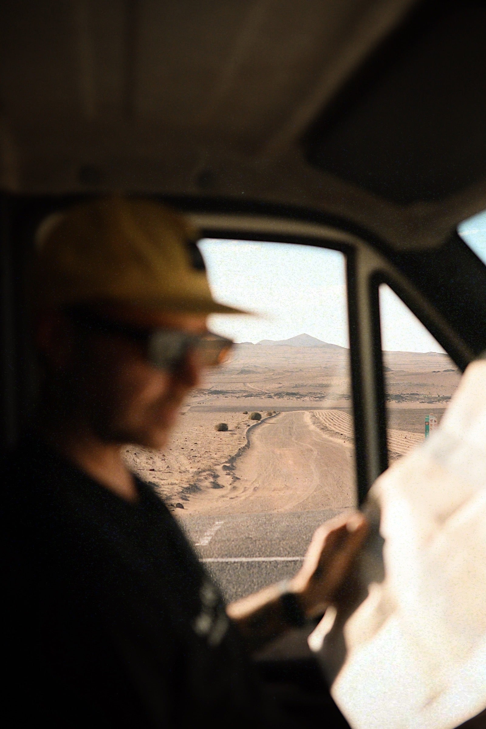 Hombre conduciendo con gafas de sol Warmouth Eyewear Rusty Rooms, reflejando luz natural, ideal para viajes y conducción