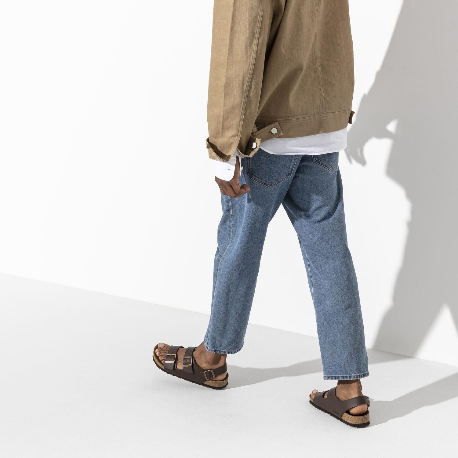 Hombre camina cómodamente con unas Chanclas Birkenstock Milano Birko-Flor en marrón oscuro