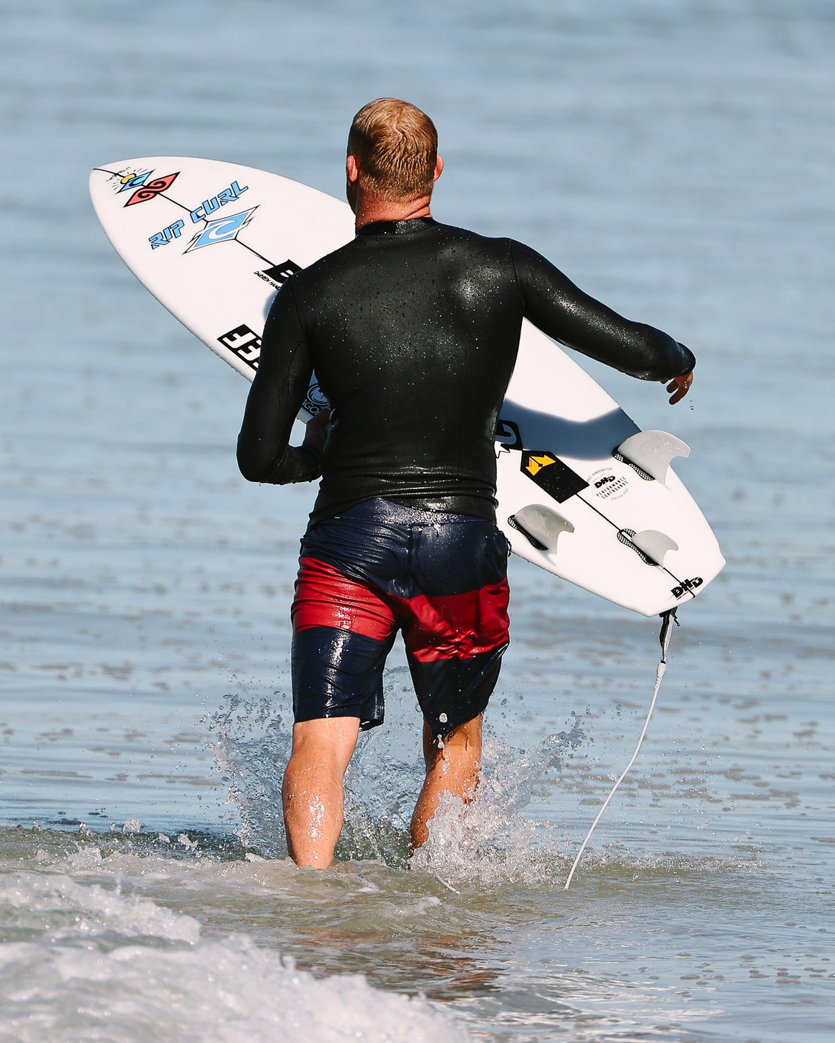 Mick Fanning en la orilla con su tabla y las quillas FCS II MF PC Twin + 1 White