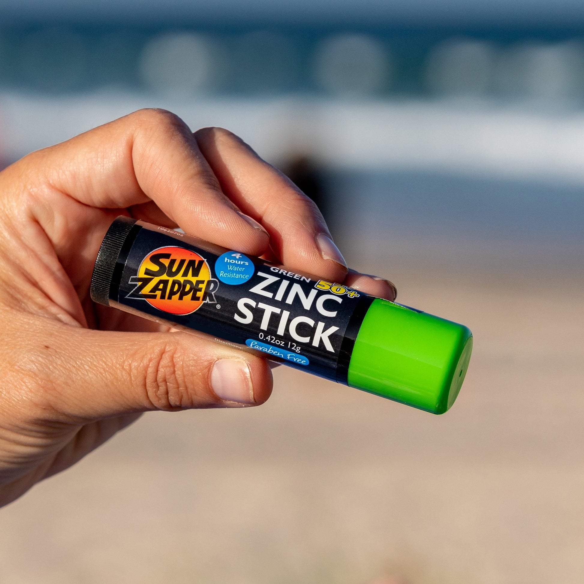 Una mano sujeta el rotector Solar en Stick Verde SPF 50+ de Sun Zapper