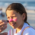 Un padre aplica a su hija el protector Solar en Stick Rosa SPF 50+ de Sun Zapper