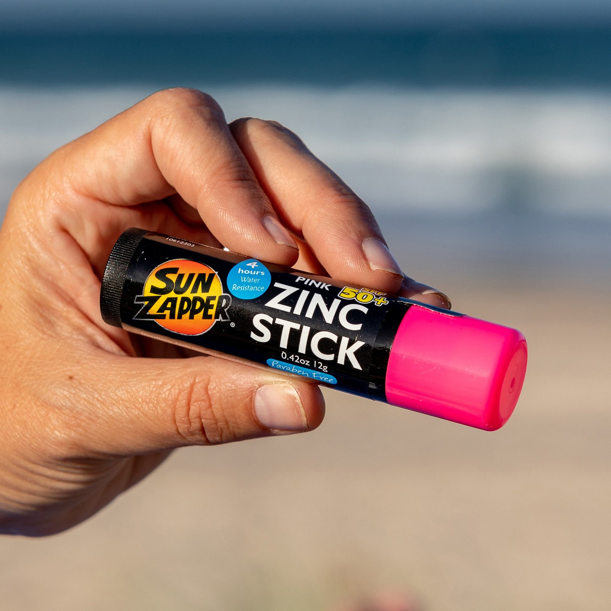 Una mano sujeta el rotector Solar en Stick Rosa SPF 50+ de Sun Zapper