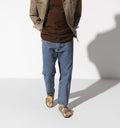 Modelo masculino con Birkenstock Arizona Plantilla Blanda cuero Tobacco Brown combinadas con vaqueros y chaqueta de trabajo en tono arena.