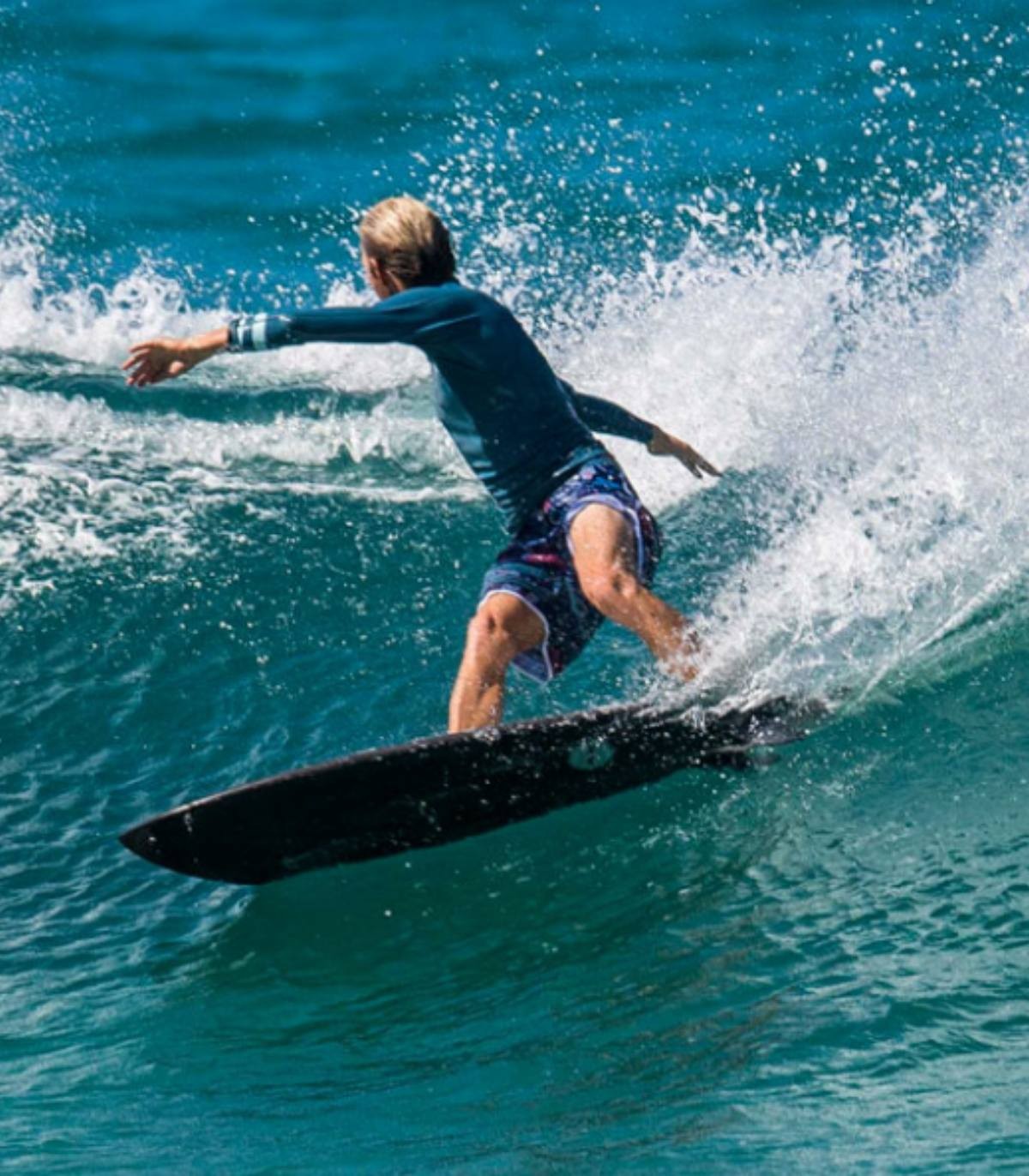 Un hombre surfea con la Tabla de surf JS Black Baron PE Carbon Fusion