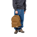 Un hombre sujeta la Mochila Carhartt WIP Jake Backpack en marrón