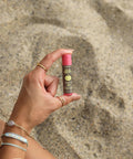 Una mano sostiene el pequeño Stick Labial de protección solar Sun Bum Original SPF 30 Sabor Granada