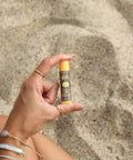 Una mano sostiene el pequeño Stick Labial de protección solar Sun Bum Original SPF 30 Sabor Mango