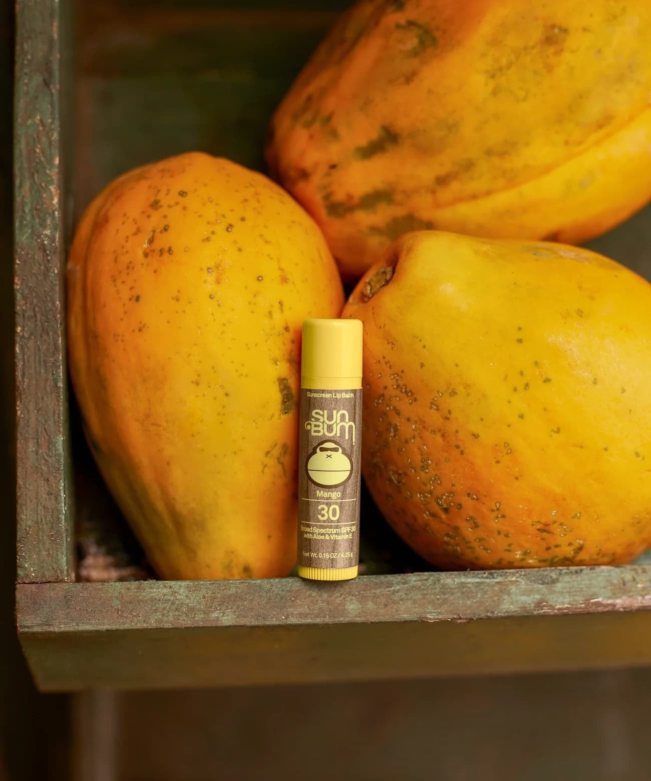 Bodegón de mangos con el Stick Labial de protección solar Sun Bum Original SPF 30 Sabor Mango en medio