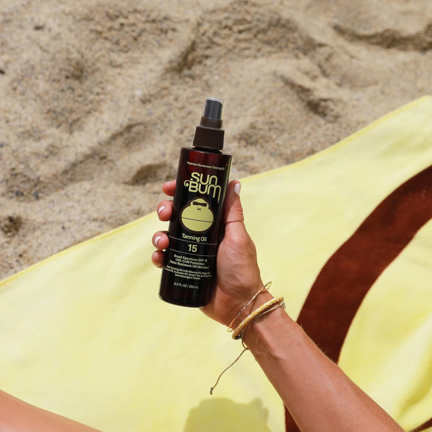 Una mano sujeta el spray de Aceite Bronceador Solar Sun Bum SPF15