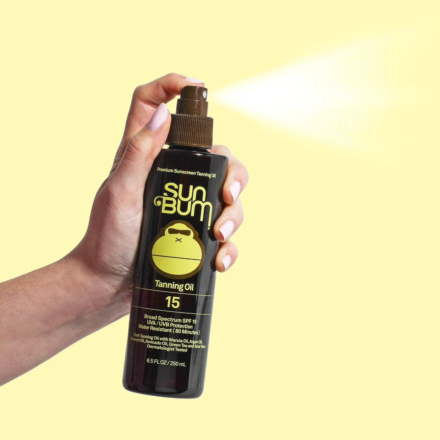 Un dedo pulsa el spray de Aceite Bronceador Solar Sun Bum SPF15, pulverizando