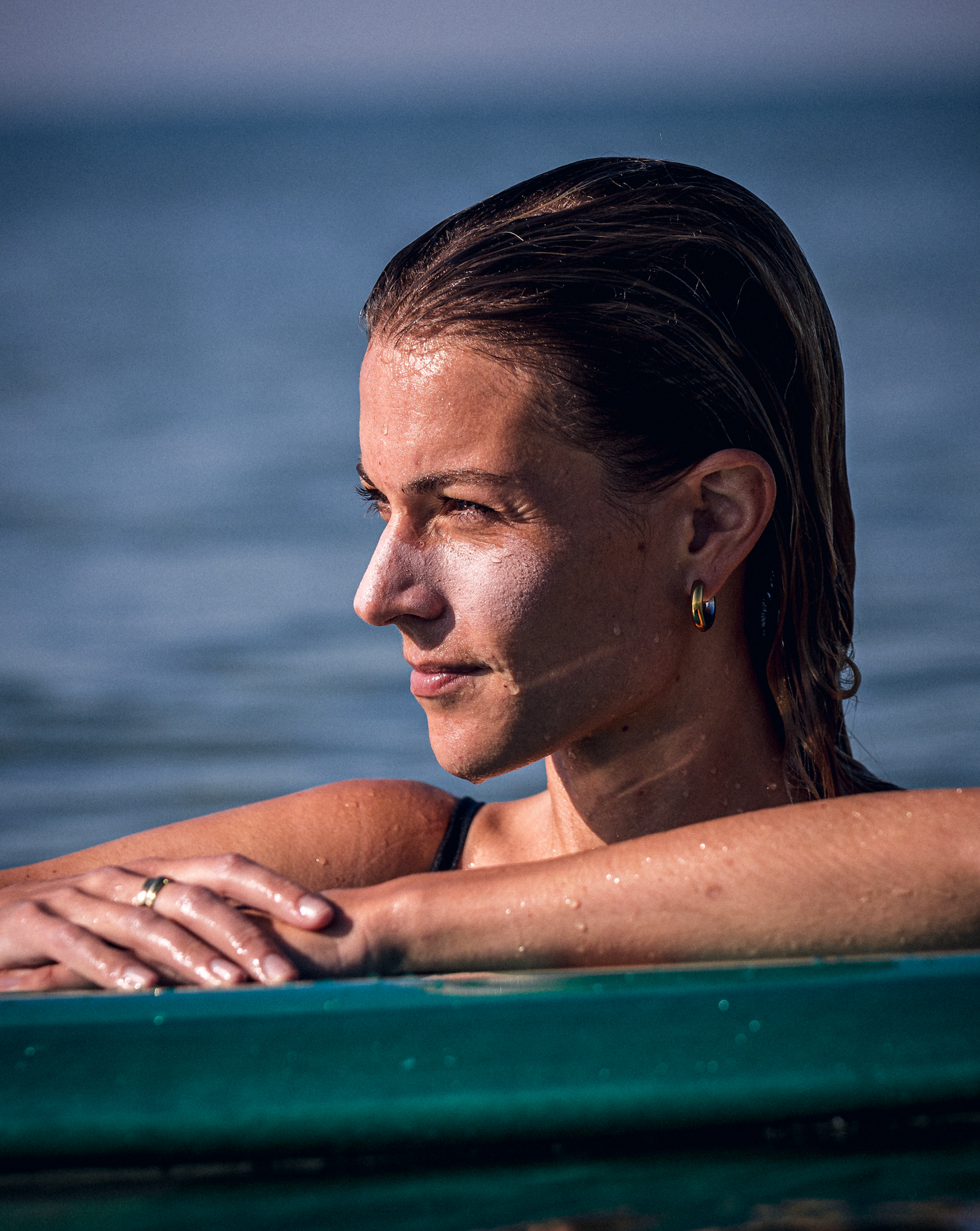 Mujer en el agua usando el stick solar Greenbush SPF 50+ blanco sobre el rostro durante una sesión de surf