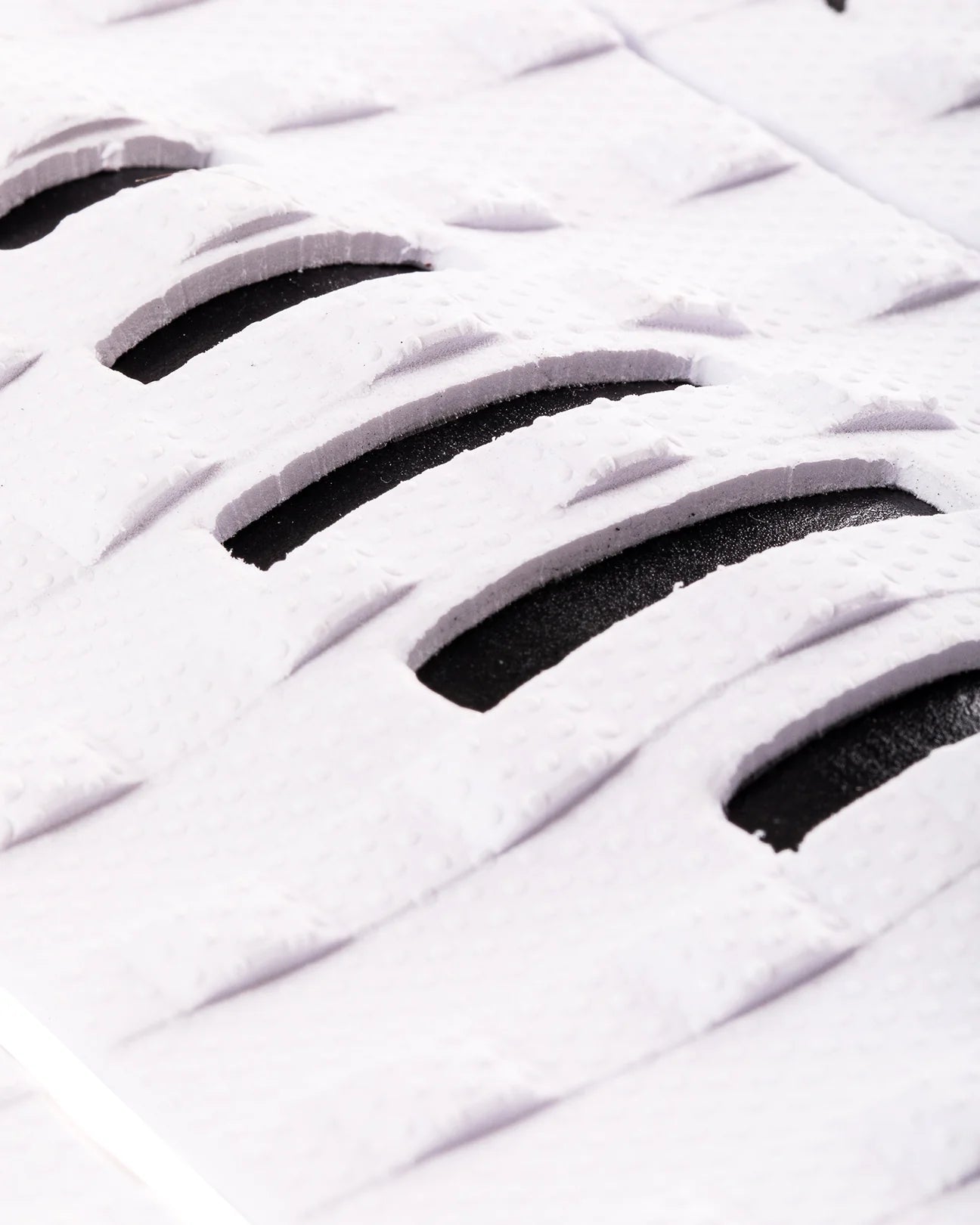 Detalle de los cortes estratégicos negros en el patrón Square Loc blanco del grip Creatures Mick Eugene Fanning Signature white black para máximo contacto del pie en tablas alternativas.