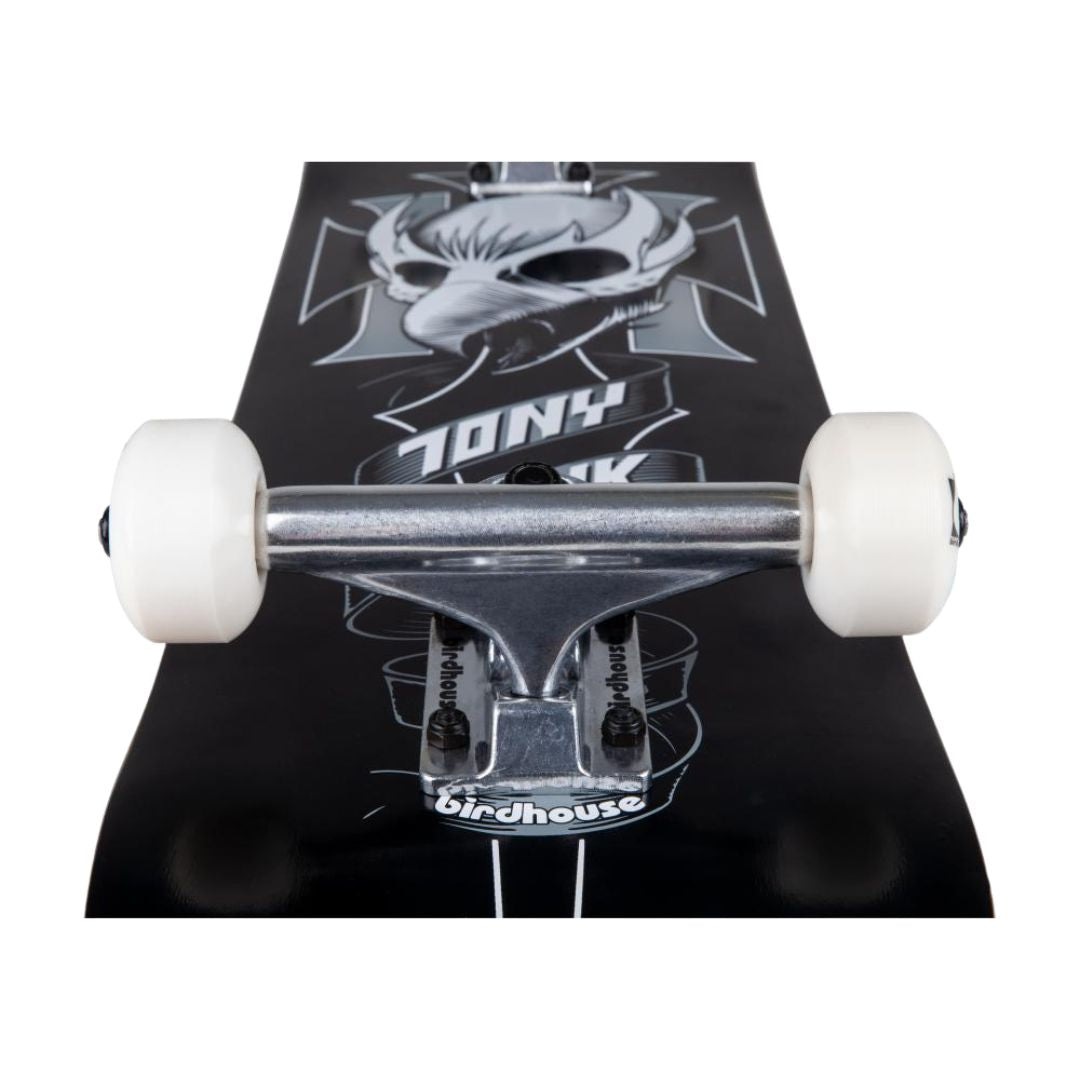 Skate completo Birdhouse Stage 1 Hawk Crest visto desde abajo en perspectiva: eje del truck plateado, ruedas blancas y calavera de ave en blanco y gris sobre base negra