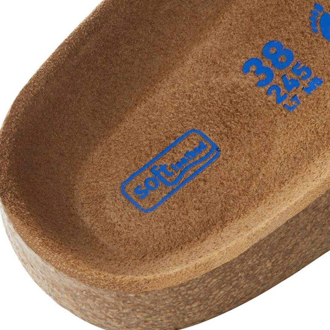 Detalle de la zona trasera de la plantilla blanda Birkenstock Arizona Tobacco Brown con sello Soft Footbed en azul y base de corcho visible en el canto