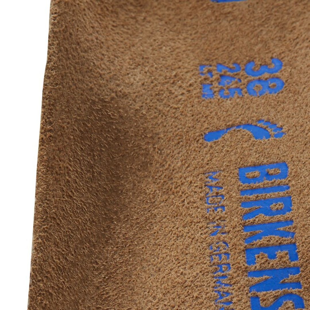 Primer plano de la superficie de ante de la plantilla Birkenstock Arizona Tobacco Brown con sello Made in Germany estampado en azul.