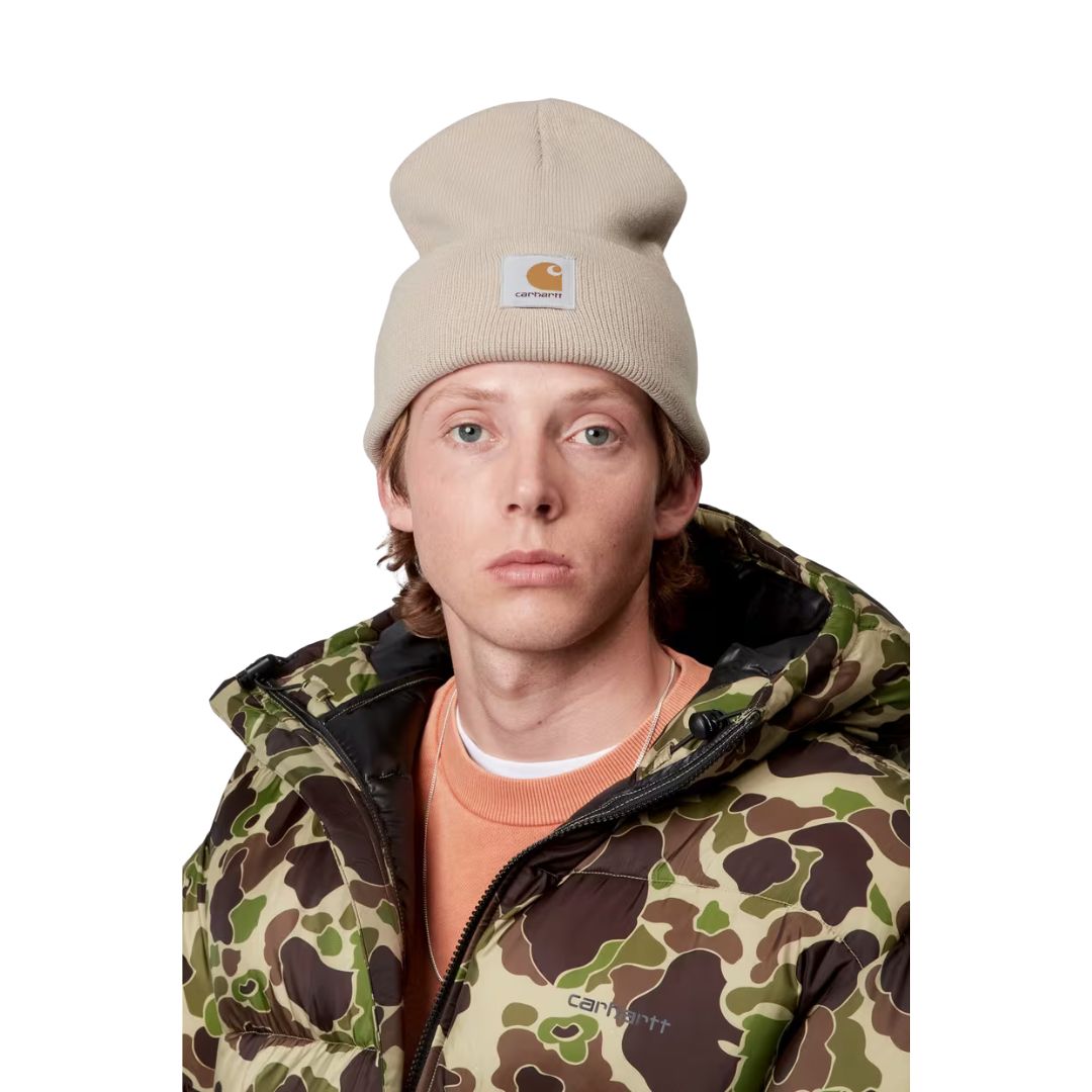 Modelo vistiendo el gorro Carhartt Acrylic Watch Hat en color Fleur de Sel, combinado con chaqueta acolchada estampada.