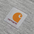 Detalle del parche frontal del gorro Carhartt Acrylic Watch Hat Grey Heather, con el logo Carhartt cosido sobre la vuelta del gorro.