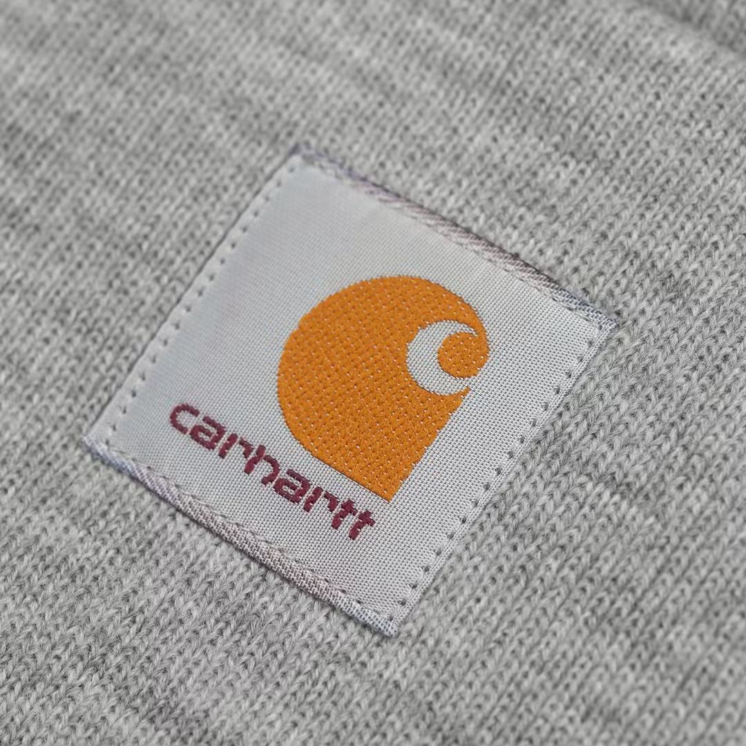 Detalle del parche frontal del gorro Carhartt Acrylic Watch Hat Grey Heather, con el logo Carhartt cosido sobre la vuelta del gorro.