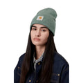 Gorro Carhartt Acrylic Watch Hat en color Velvet Green Heather, mostrado en un modelo que lleva chaqueta vaquera azul.