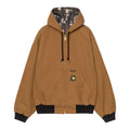 Vista frontal de la chaqueta Carhartt WIP 50 Years Anniversary OG Active Jacket en color marrón canvas con capucha y forro interior de camuflaje.