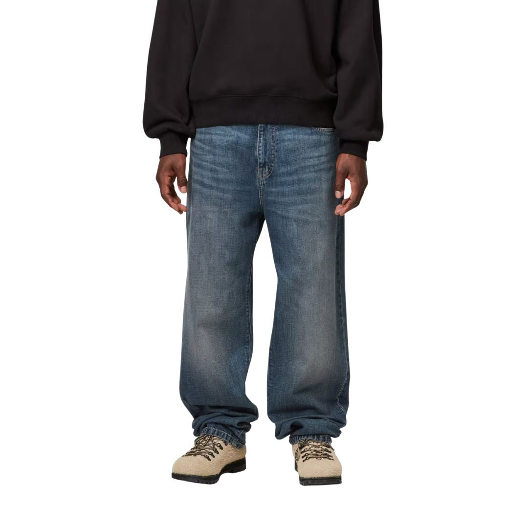 Detalle frontal Carhartt WIP Aaron Pant Blue Stone Washed en modelo mostrando ajuste regular tapered y acabado denim lavado.