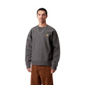 Sudadera Carhartt WIP American Script gris grafito puesta por un modelo, primer plano del pecho mostrando el logotipo bordado bicolor Carhartt sobre el tejido gris grafito.
