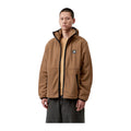 Modelo de frente con la chaqueta forro polar ligero Carhartt WIP Blevin Liner en color WIP H Brown, con capucha, cremallera central en contraste y etiqueta en el pecho.