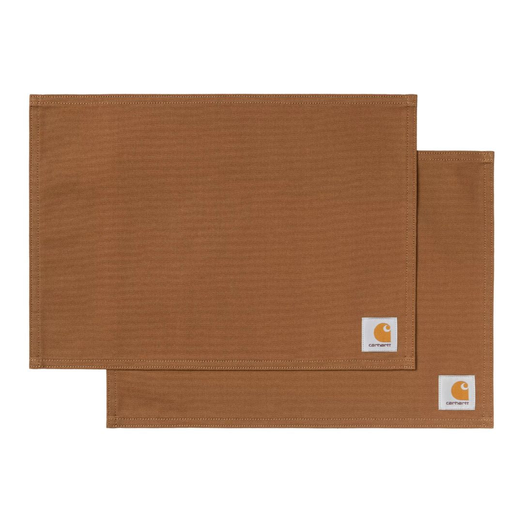 Carhartt WIP Canvas Table Set en color Hamilton Brown, dos manteles individuales de canvas de algodón sobre fondo blanco, con etiqueta cuadrada tejida en la esquina.