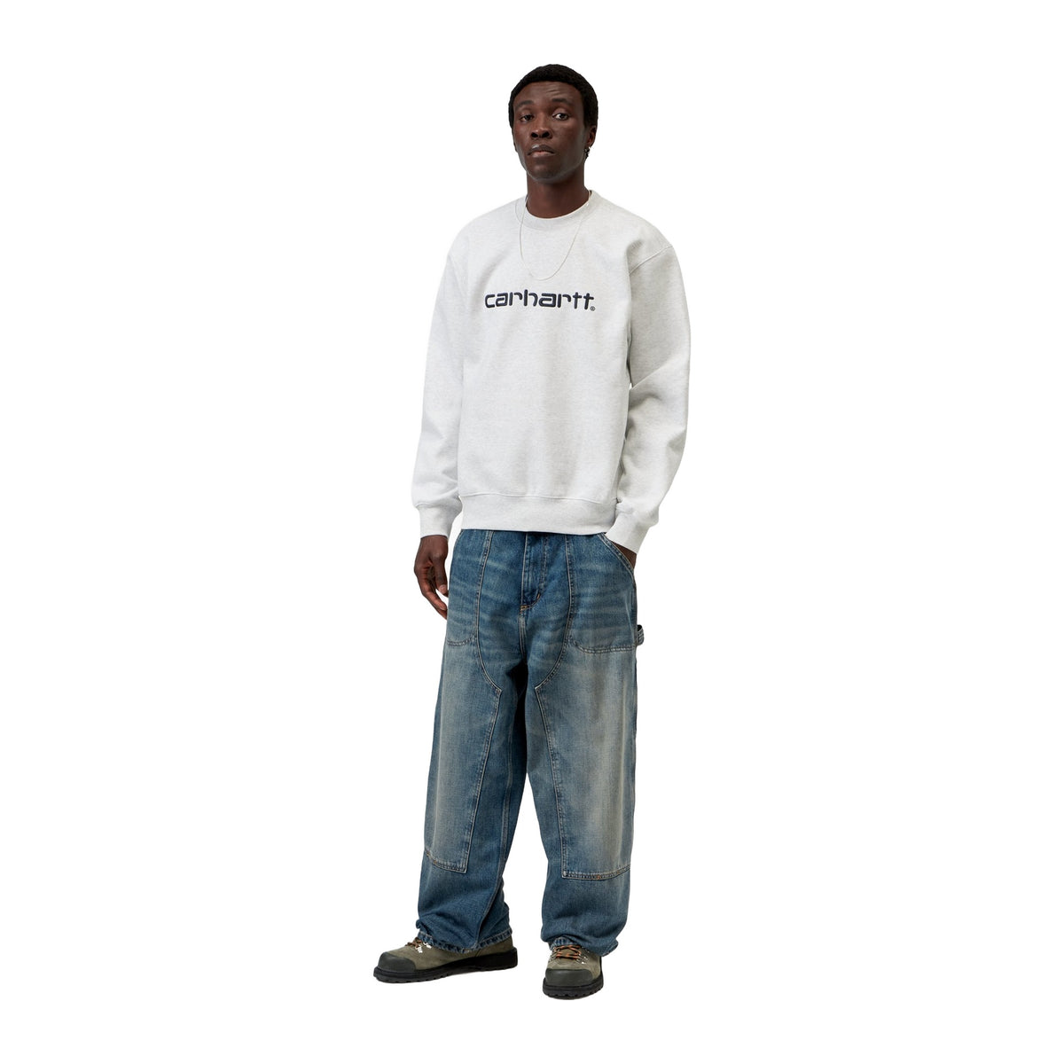 Modelo de cuerpo entero con la sudadera Carhartt WIP Carhartt Sweat en color Ash Heather / Graphite, combinada con vaqueros anchos desgastados y zapatillas.