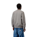 Vista trasera de modelo luciendo la sudadera Carhartt WIP Carhartt Sweat en Shady Grey, mostrando el ajuste oversize en hombros y mangas junto a vaqueros Carhartt WIP con parche trasero.