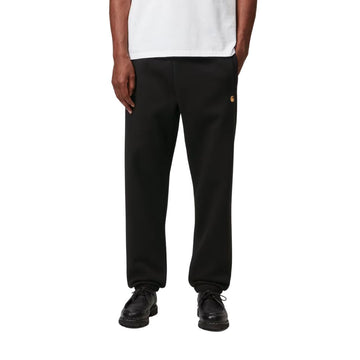 Modelo con Carhartt WIP Chase Sweat Pant en ash heather, primer plano frontal desde la cintura. Muestra la cintura elástica ajustable y el logo "C" bordado en dorado.
