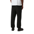Modelo con Carhartt WIP Chase Sweat Pant en ash heather, vista trasera. Se aprecia el bolsillo trasero con solapa y la caída holgada del punto cepillado.