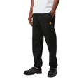 Modelo con Carhartt WIP Chase Sweat Pant en ash heather, primer plano lateral. Se distingue con detalle el logo 