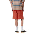 Carhartt WIP Chase Swim Trunks en color oxide red con detalle dorado, vista trasera sobre modelo masculino. Bañador de poliéster repelente al agua en rojo teja con bolsillo trasero y cinturilla elástica. Corte regular fit.