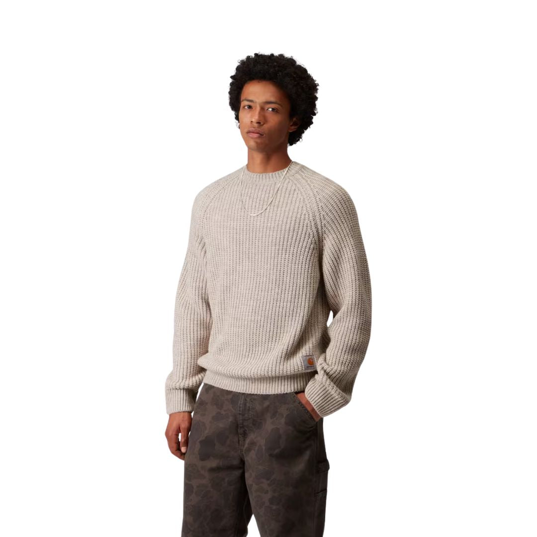 Modelo masculino vistiendo el Carhartt WIP Firth Sweater en color Fleur de Sel, vista lateral del jersey.