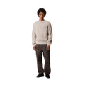 Modelo masculino vistiendo el Carhartt WIP Firth Sweater en color Fleur de Sel, vista frontal completa.