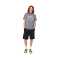 Carhartt WIP Flint Short en color negro teñido en prenda, vista completa de look sobre modelo masculino. Bermuda de sarga orgánica de corte regular combinada con camiseta de rayas azul marino con estampado Carhartt WIP Class of 89, calcetines blancos y botines de ante beige.