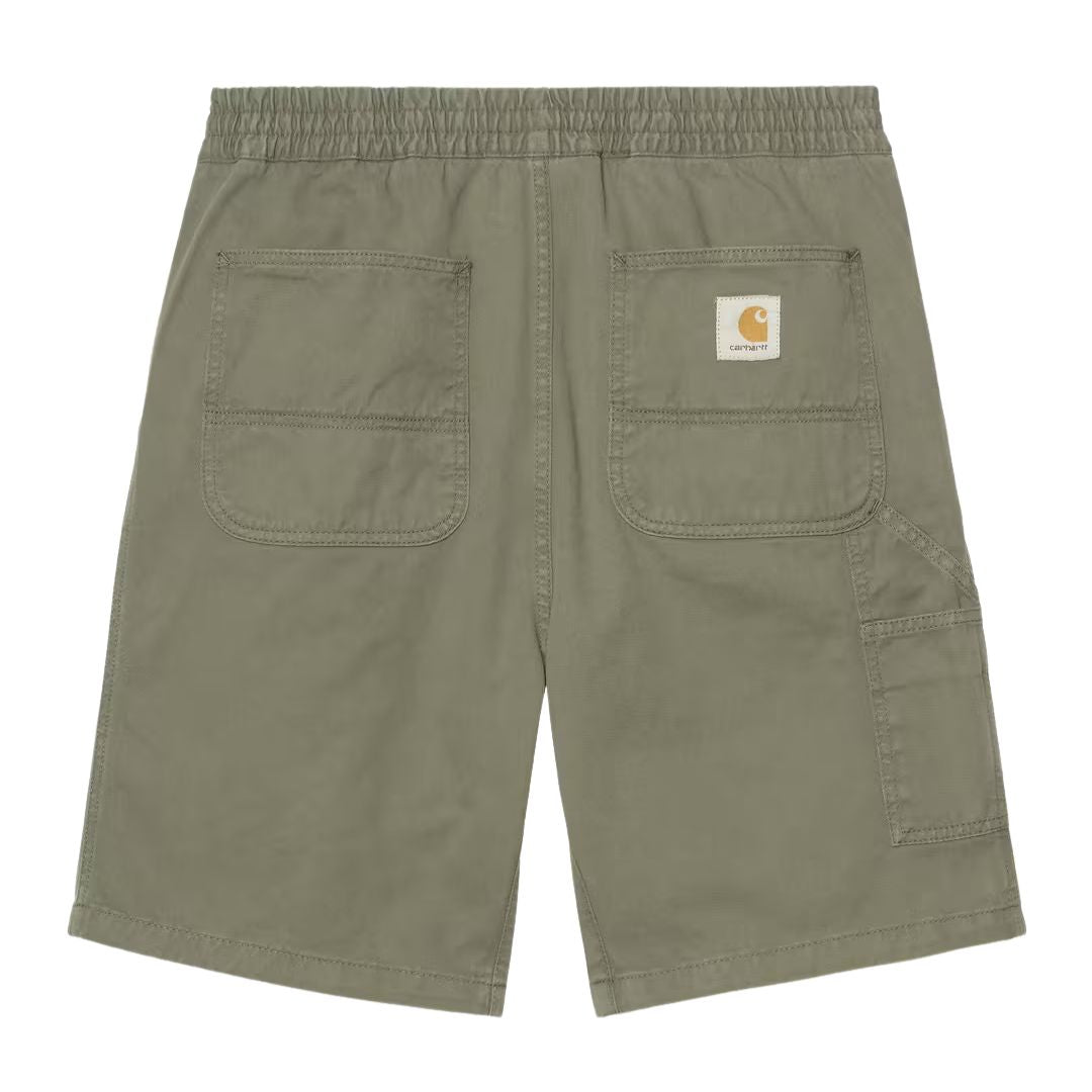 Carhartt WIP Flint Short en color verde leaf teñido en prenda, vista trasera plana. Bermuda de algodón orgánico con cinturilla elástica fruncida, dos bolsillos traseros de parche con costuras reforzadas, bolsillo para herramientas en la pierna derecha y etiqueta cuadrada tejida Carhartt WIP centrada en la parte trasera.