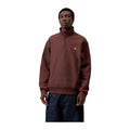 Modelo de frente con la sudadera de cuello alto y media cremallera Carhartt WIP Half Zip American Script Sweat en color Amarone, con el logotipo bordado en el pecho.