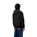 Vista trasera del modelo con la chaqueta Carhartt WIP Hooded Sail Jacket negra, mostrando la caída y corte regular.