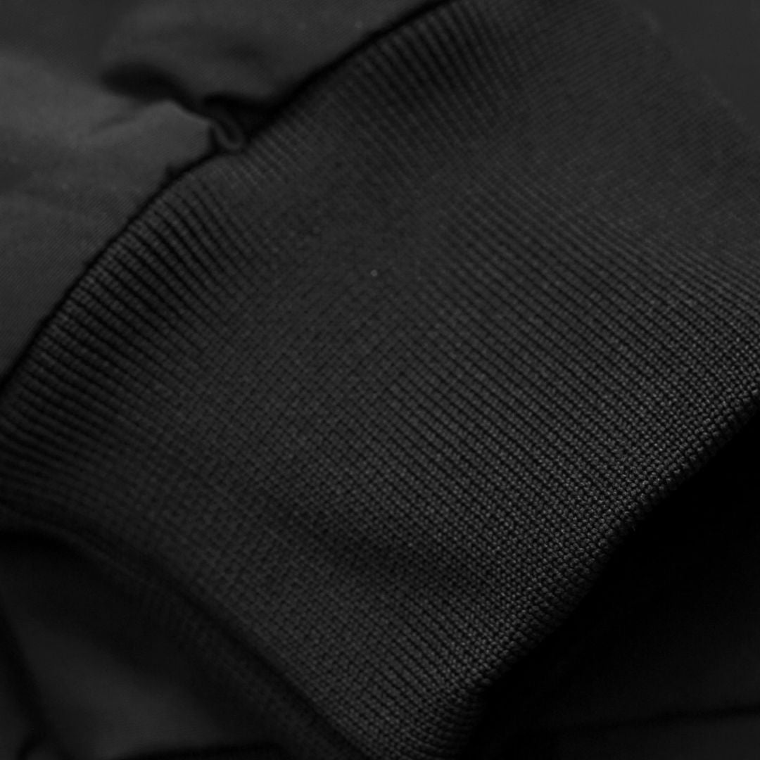Detalle del puño acanalado de la chaqueta Carhartt WIP Hooded Sail Jacket en color negro, con tejido elástico resistente.