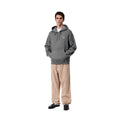 Modelo con la Carhartt WIP Hooded Vista Sweat en color negro garment dyed y pantalón de pana beige, mostrando de cuerpo entero el corte oversize y la capucha con forro guateado.