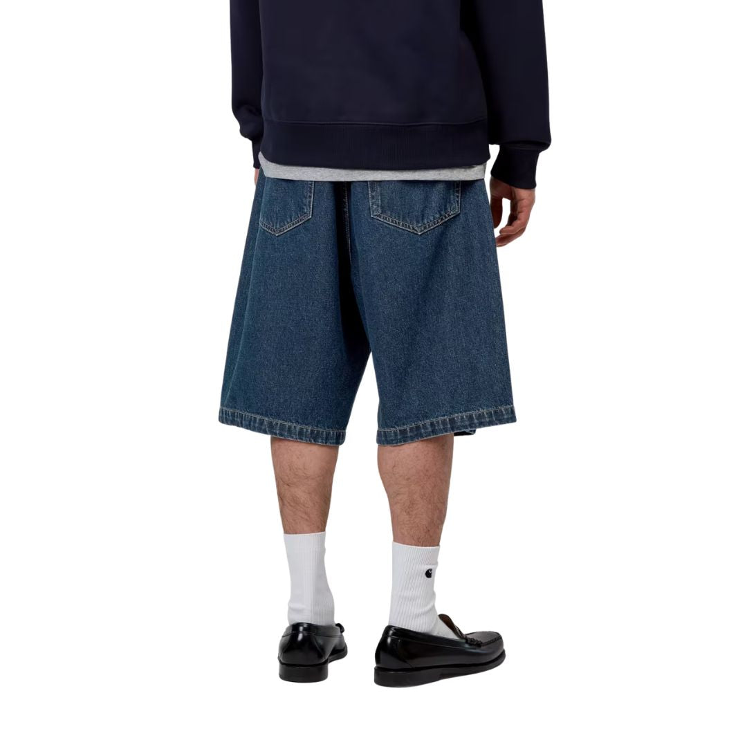 Carhartt WIP Landon Short azul stone washed, vista trasera en modelo, amplitud de pierna y bolsillos traseros con costuras en contraste ocre.