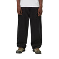 Carhartt WIP Landon Pant black tone washed en plano frontal sobre modelo, con el bajo acumulado sobre las botas, típico del ajuste ancho y relajado del modelo.